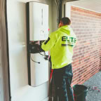 Electrician working on a solar inverter installation inside a garage in New South Wales, Australia.